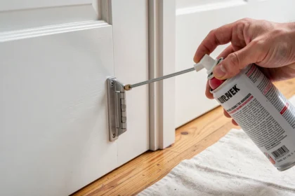 Pulvérisation d'un produit sur le gond d'une porte intérieure blanche